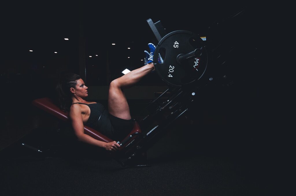 Femme qui s'entraîne sur une presse dans une salle de musculation