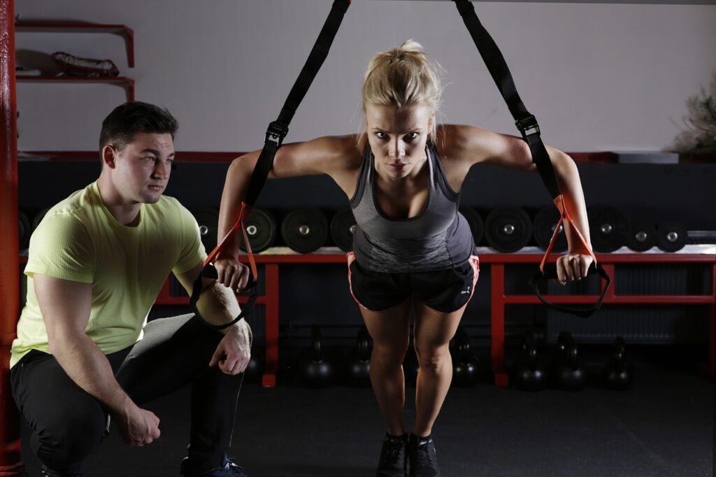 Femme qui s'entraine à la salle de sport avec un coach